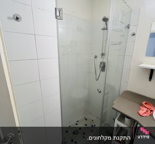 מקלחון זכוכית עם ראש מקלחת ומדף מתכת